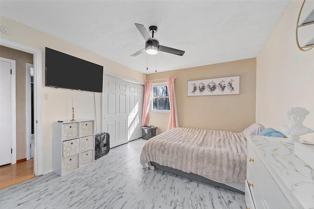 bedroom featuring a textured ceiling, marble finish floor, a closet, and a ceiling fan