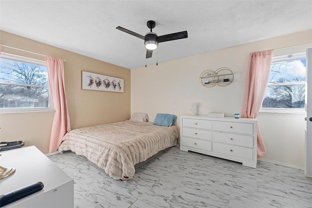 bedroom featuring marble finish floor, a ceiling fan, and a textured ceiling