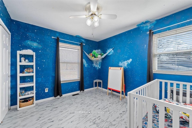 bedroom with ceiling fan, a crib, and baseboards