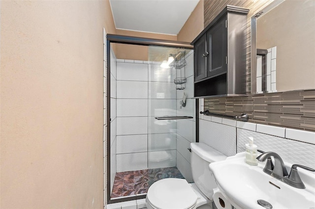 bathroom featuring toilet, a sink, tile walls, a shower stall, and decorative backsplash