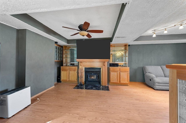 living room with ceiling fan, a textured ceiling, visible vents, and wood finished floors