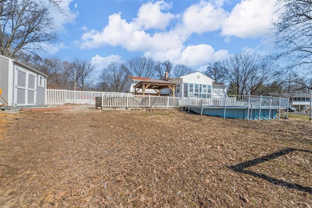 view of yard featuring an outdoor pool, a gazebo, fence, a shed, and an outdoor structure