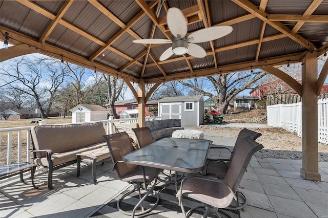 view of patio with outdoor dining area, a gazebo, fence, a shed, and an outdoor structure