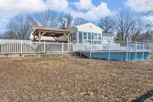 back of property with a chimney, fence, an outdoor pool, and a gazebo