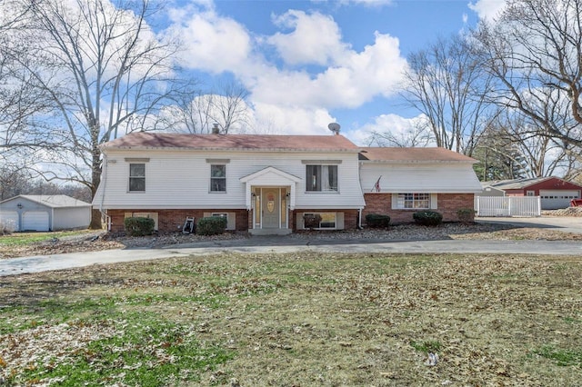 split foyer home featuring brick siding, a detached garage, and an outbuilding