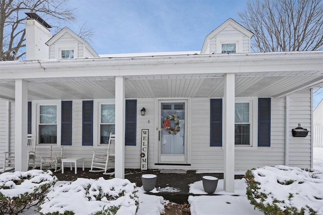 snow covered property entrance featuring covered porch