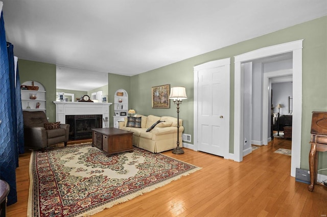 living room featuring built in shelves and light hardwood / wood-style flooring