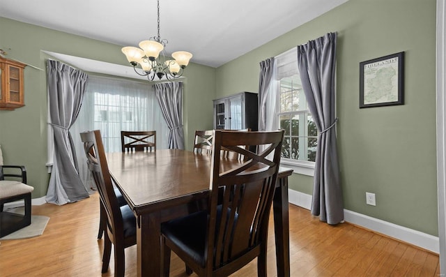 dining area with light wood-type flooring and an inviting chandelier