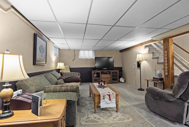 carpeted living room with a paneled ceiling and wooden walls