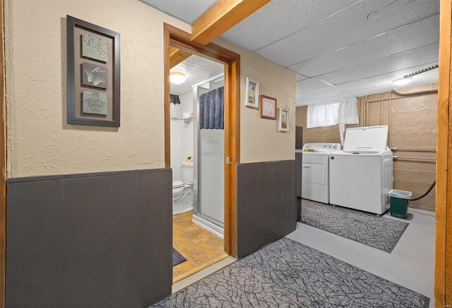 clothes washing area with separate washer and dryer and wooden walls