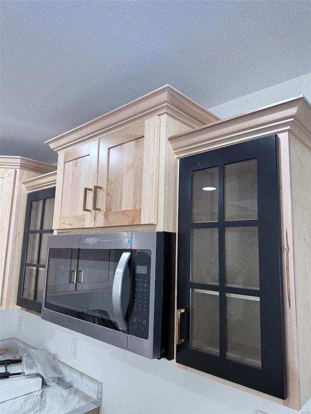 interior space with light brown cabinetry, stainless steel microwave, and light countertops