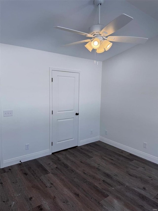 empty room featuring dark wood-style flooring, a ceiling fan, and baseboards