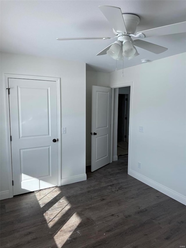 interior space featuring dark wood-style flooring, a ceiling fan, and baseboards