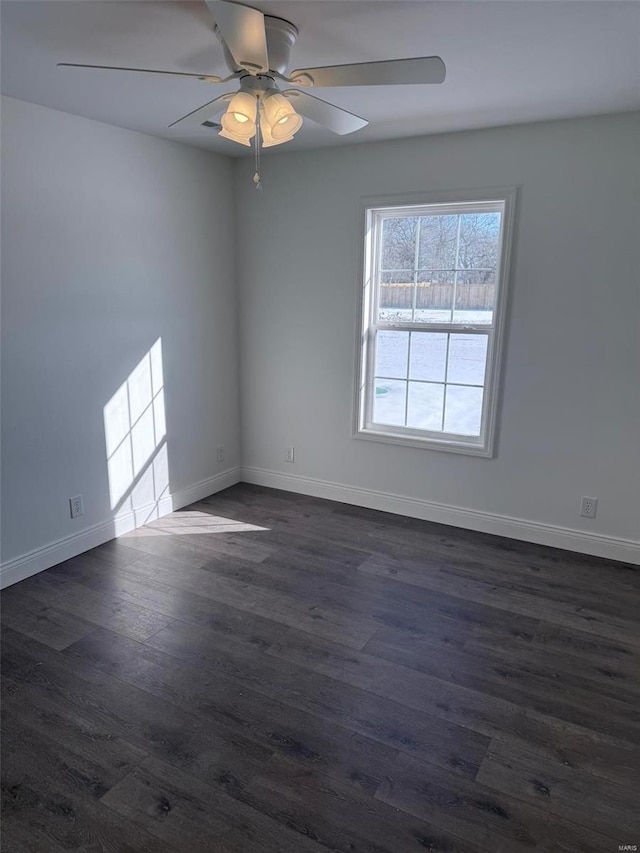 spare room with a ceiling fan, dark wood-style flooring, and baseboards