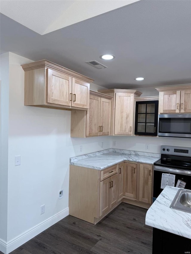 kitchen with light brown cabinets, visible vents, appliances with stainless steel finishes, light stone countertops, and dark wood-style floors