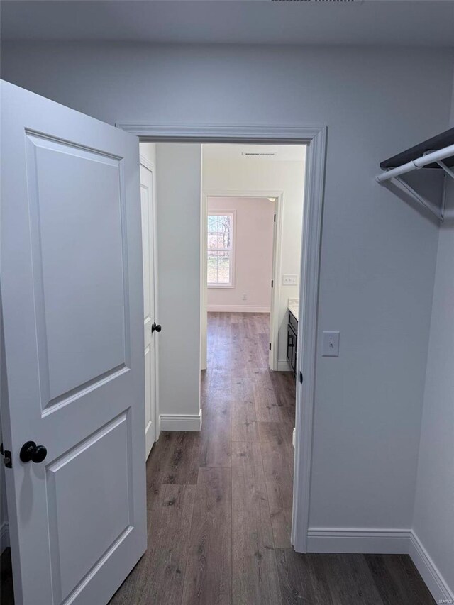 corridor with dark wood finished floors and baseboards