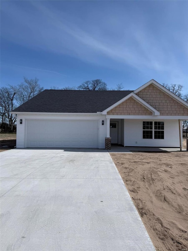 view of front facade with a garage, concrete driveway, and a shingled roof