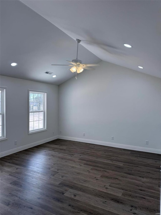 empty room featuring baseboards, visible vents, dark wood-style flooring, vaulted ceiling, and recessed lighting