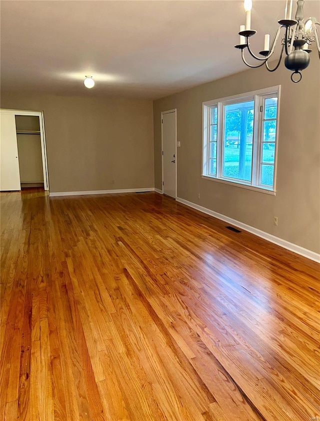 spare room featuring hardwood / wood-style floors and a notable chandelier