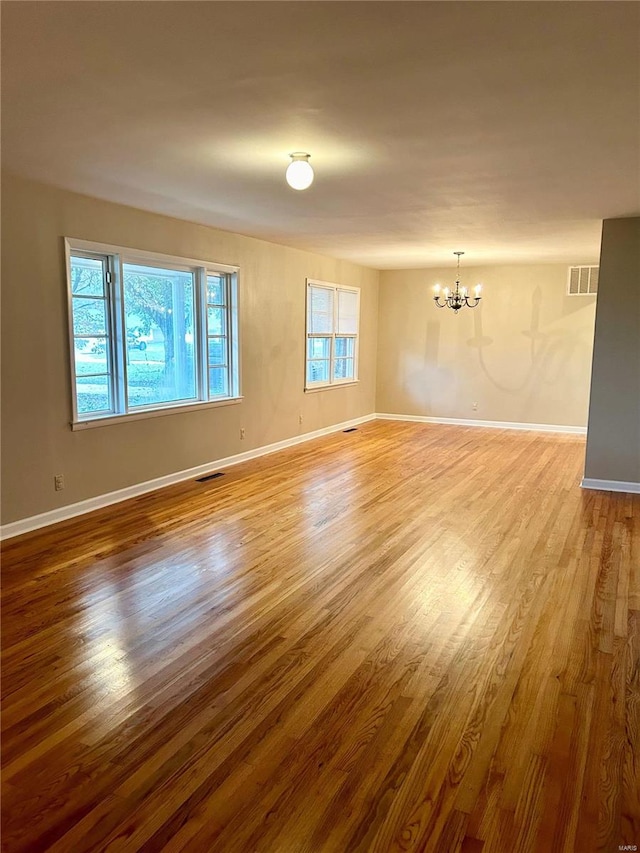 empty room with light hardwood / wood-style floors and a chandelier