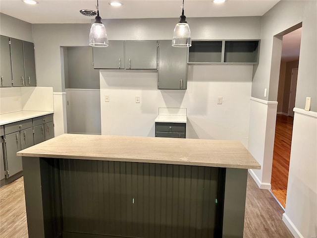 kitchen with gray cabinets, decorative light fixtures, and light hardwood / wood-style flooring