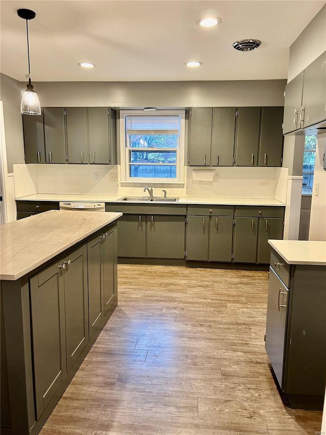 kitchen with a center island, sink, hanging light fixtures, gray cabinets, and light wood-type flooring