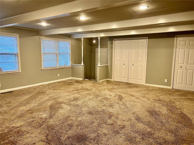 unfurnished bedroom with carpet, multiple windows, and beamed ceiling