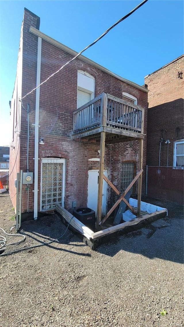 rear view of property with central AC unit and a balcony