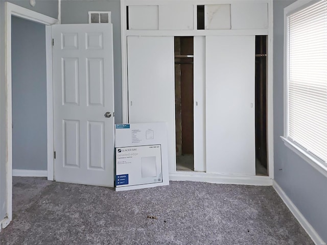 unfurnished bedroom with dark carpet and a closet