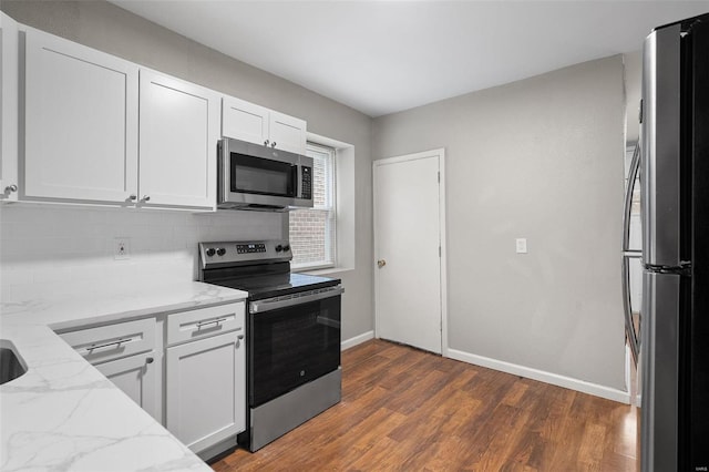 kitchen with white cabinets, dark hardwood / wood-style floors, light stone counters, and stainless steel appliances