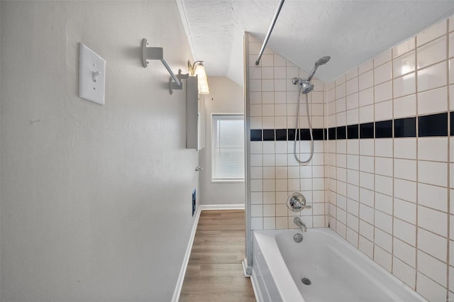 bathroom featuring hardwood / wood-style floors, a textured ceiling, tiled shower / bath, and lofted ceiling