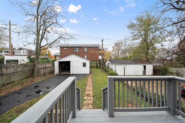 wooden deck featuring an outbuilding, a yard, and a garage