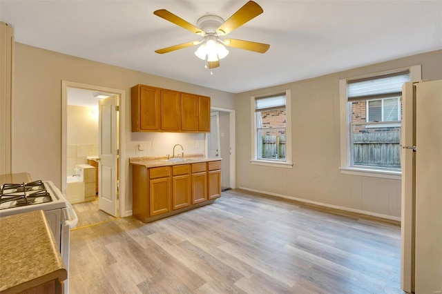 kitchen featuring white appliances, light hardwood / wood-style flooring, ceiling fan, and sink