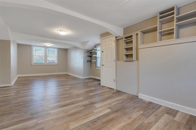 interior space with a textured ceiling, lofted ceiling, and light wood-type flooring