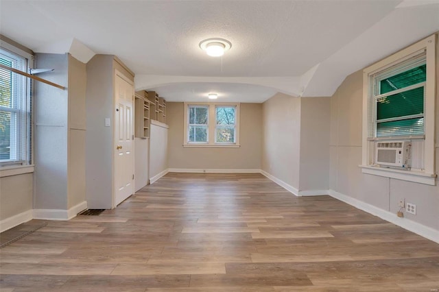 empty room with cooling unit, light hardwood / wood-style floors, and a textured ceiling