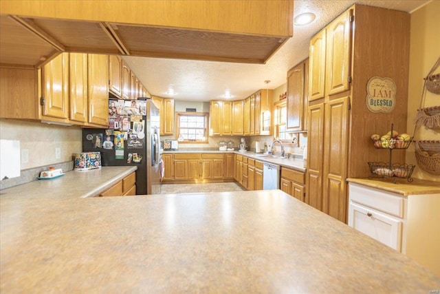 kitchen with sink, kitchen peninsula, appliances with stainless steel finishes, and a textured ceiling