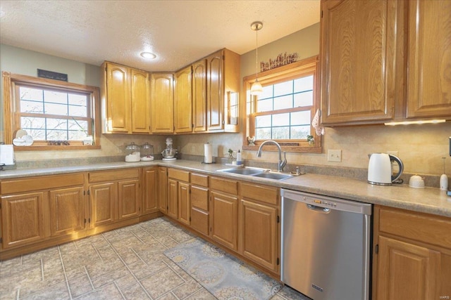 kitchen featuring decorative light fixtures, sink, a textured ceiling, and stainless steel dishwasher