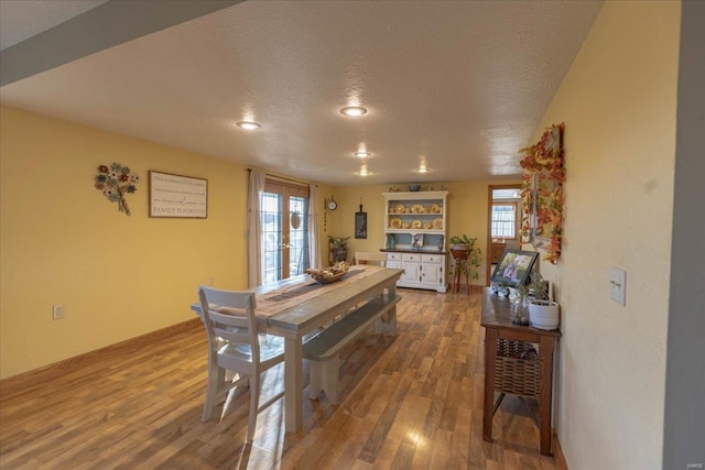 dining room featuring hardwood / wood-style floors, a textured ceiling, and french doors