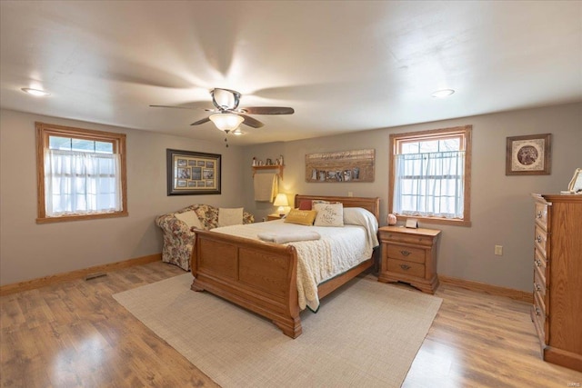 bedroom featuring ceiling fan, light hardwood / wood-style floors, and multiple windows