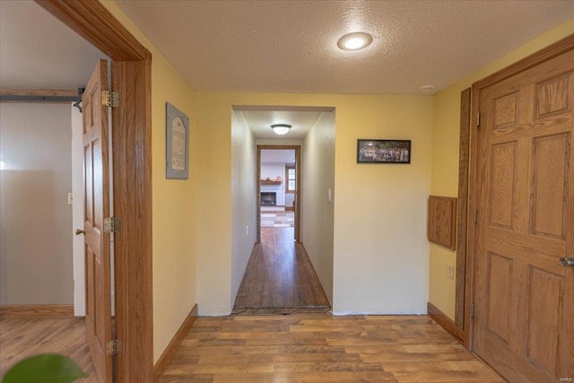 hallway featuring light wood-type flooring and a textured ceiling