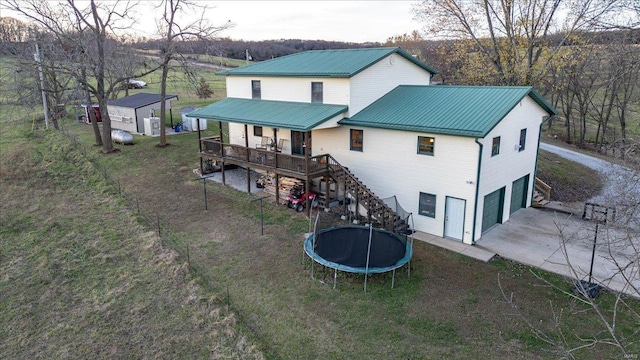 back of house featuring a trampoline and a garage