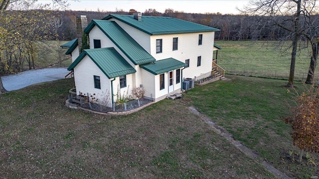 rear view of house with cooling unit and a yard