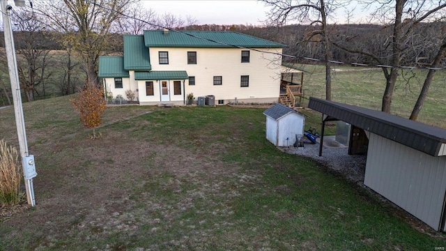 rear view of house featuring central AC, a storage shed, and a yard