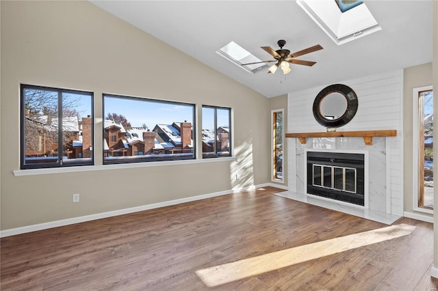 unfurnished living room featuring hardwood / wood-style flooring, ceiling fan, and vaulted ceiling with skylight