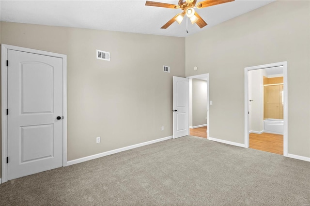 unfurnished bedroom with ceiling fan, ensuite bath, vaulted ceiling, and light carpet