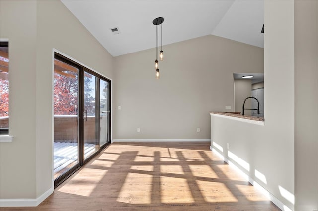 unfurnished dining area featuring lofted ceiling and light hardwood / wood-style floors