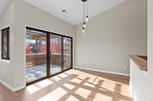 unfurnished dining area featuring lofted ceiling and light hardwood / wood-style flooring