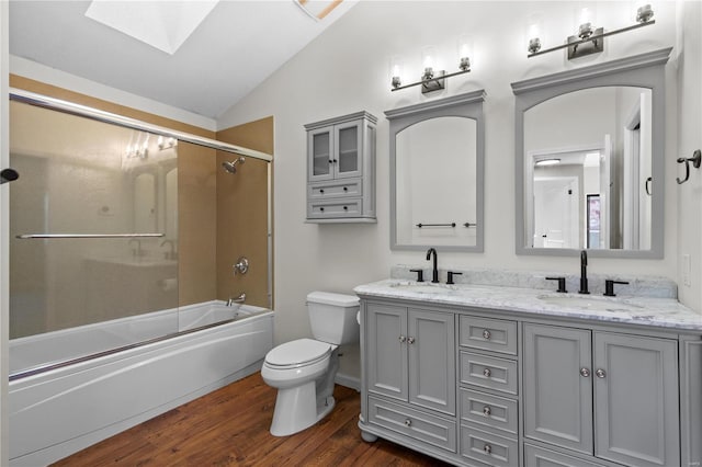 full bathroom featuring bath / shower combo with glass door, vaulted ceiling with skylight, vanity, wood-type flooring, and toilet