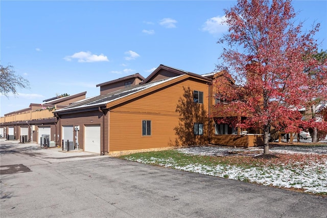 view of property exterior with a garage and central AC unit