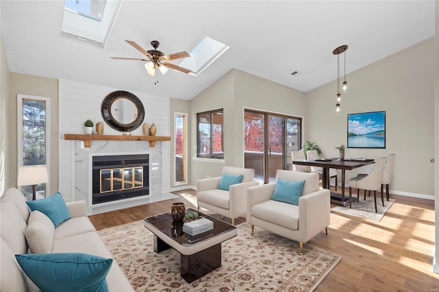 living room with a healthy amount of sunlight, vaulted ceiling with skylight, and light wood-type flooring